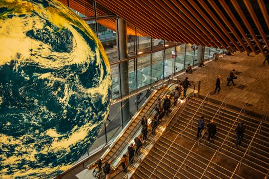 A high angle view of a bustling urban station, featuring escalators and a giant globe.