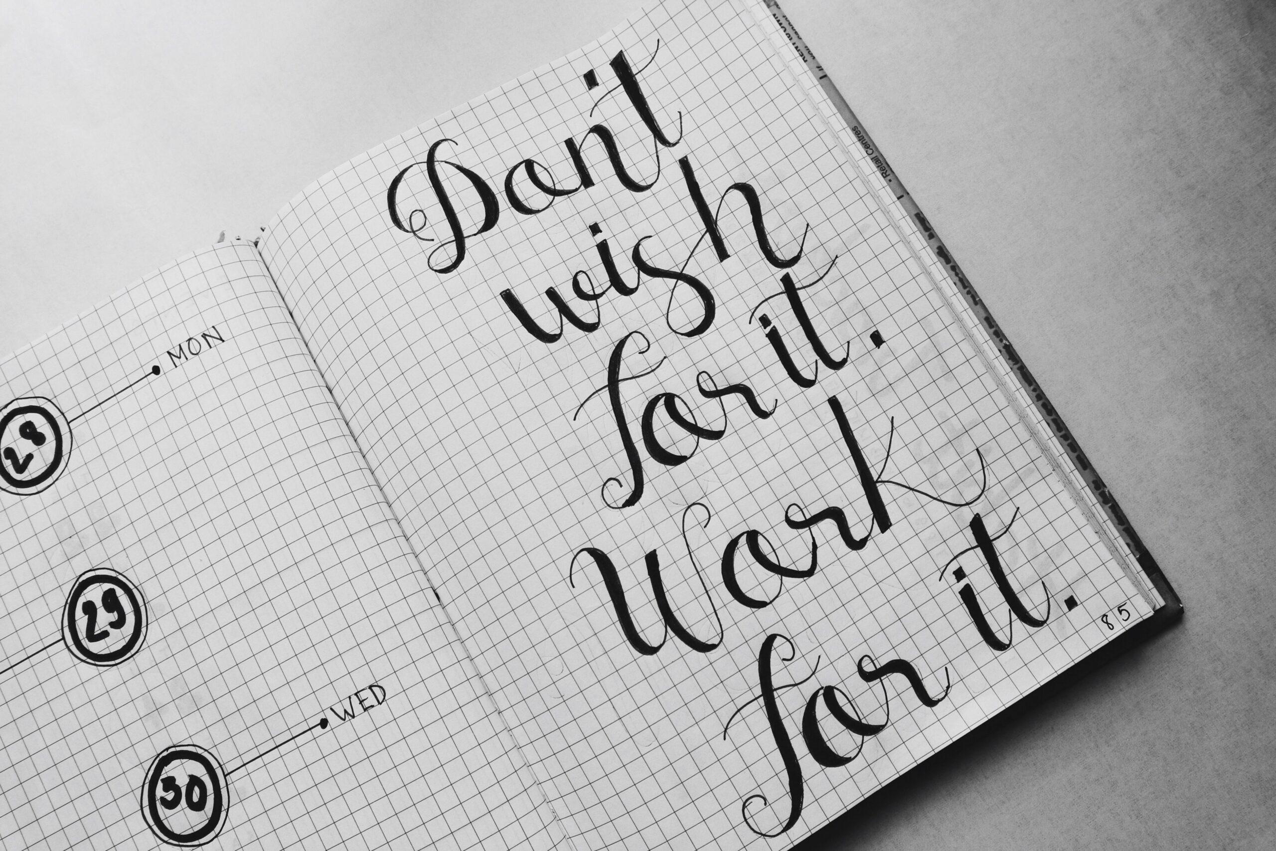 Close-up of motivational calligraphy on grid paper, inspiring message for productivity.